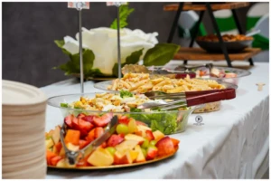Buffet spread featuring fruit salad, pasta salad, and green salad in glass bowls.