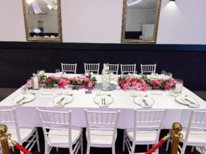 Decorated banquet table with white tablecloth, pink runner, and pink floral centerpieces.