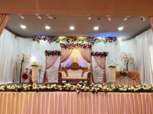 Decorated event stage with white sofa, floral arrangements, and drapes.
