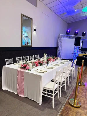 Decorated banquet table with white tablecloth, pink runner, and pink floral centerpieces.