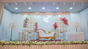 Decorated event stage with white couch, gold arches, and pink floral accents.